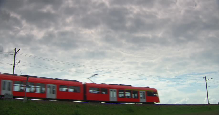 Orange train passing through a field on a cloudy day