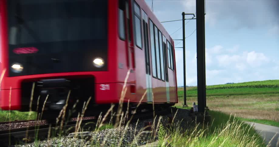 Passenger train passes a cyclist heading the other way through rural farmland on a misty day