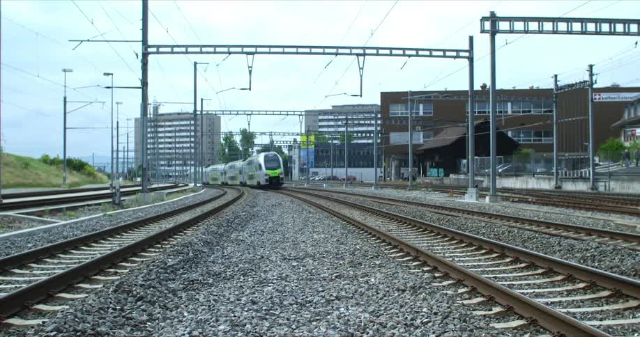 Train passing through the rail on an urban area surrounded by buildings outdoors during daytime