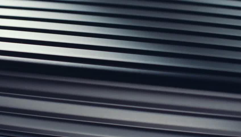 A closeup of a metal surface with parallel ridges creating a reflective pattern
