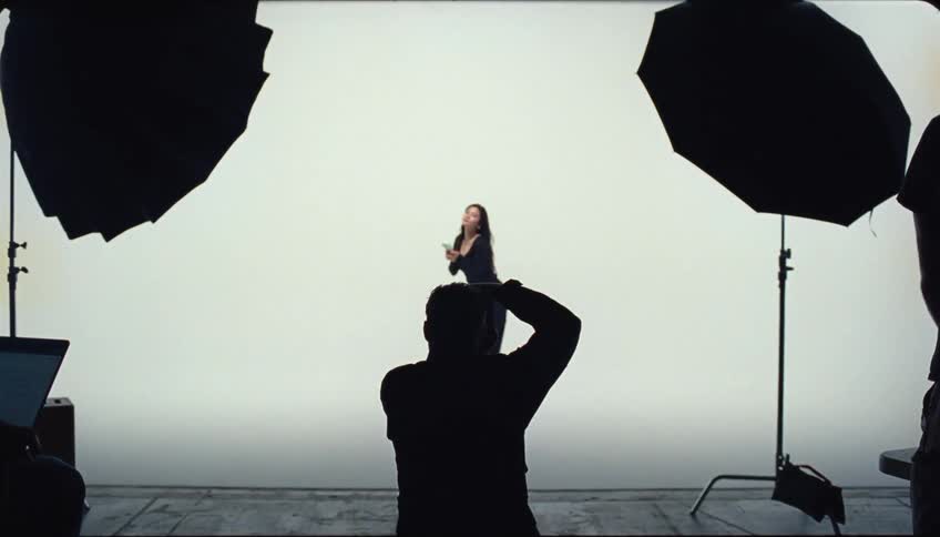A photographer is taking a picture of a person posing in a studio with large lighting equipment on either side