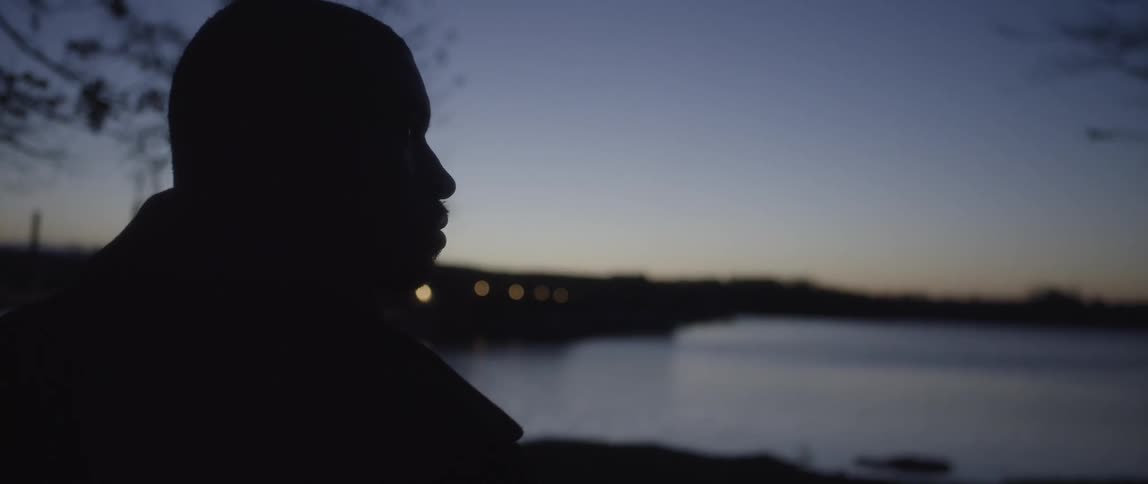 Man looking out over a body of water at sunset
