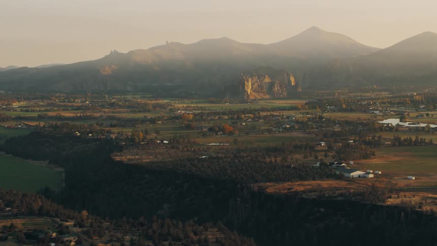 Aerial panorama of a valley with rural houses and mountain ranges in the background