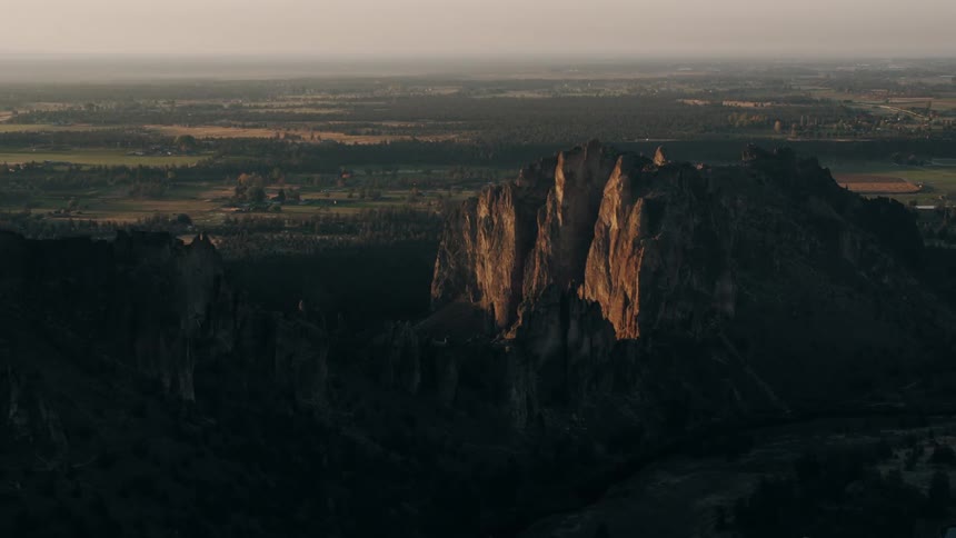 Aerial landscape of mountains and ruins with a small town on the horizon