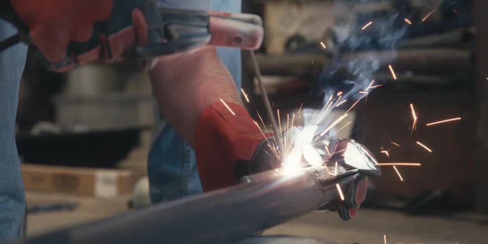 Hand with gloves welding a metal with a tool
