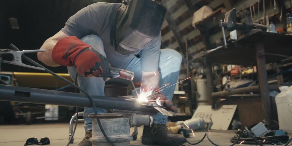 Man in a workshop welding metal with a tool and emitting sparks