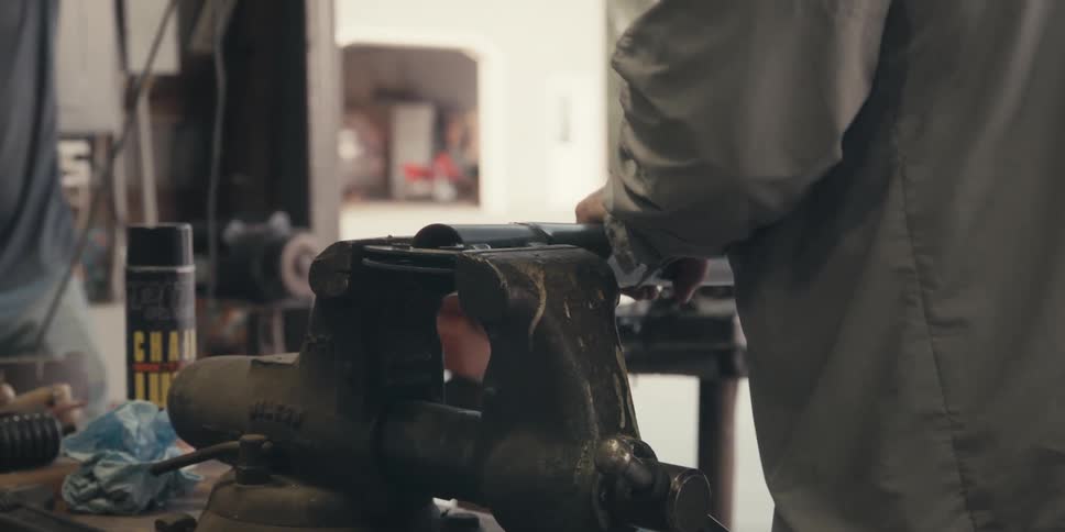 Two people working in a workshop with one of them touching a piece of steel equipment