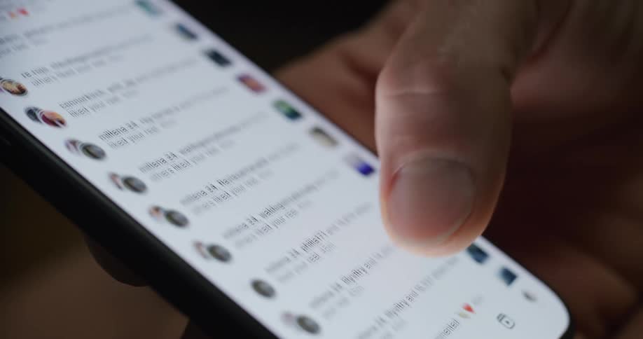 A finger scrolls through a list of instagram notifications on a smartphone screen