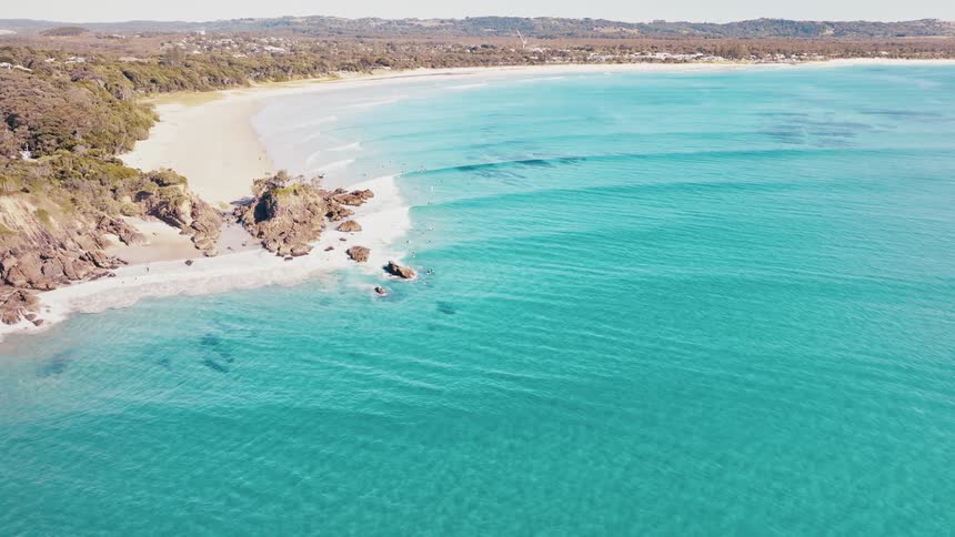 Aerial view of a pristine beach with turquoise waters rocky outcrops and a sandy shoreline