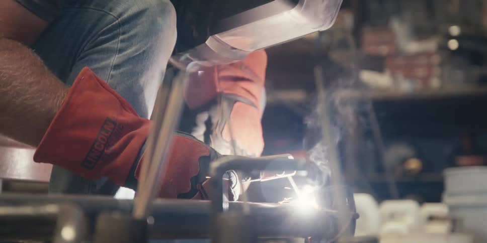 Man in protective gloves and mask welding an object