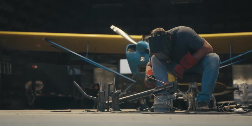 Man with mask and protective glove working in a workshop welding a metal