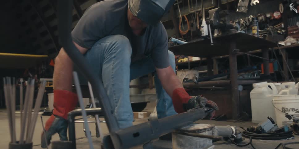A person in protective gear is welding metal pieces together with bright sparks flying