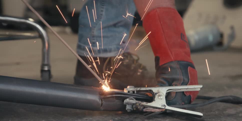 Male welder welds a project resting on the floor