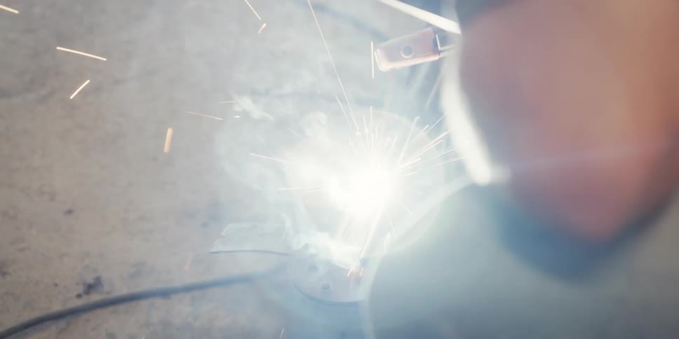 Smoke rises from the project a man is welding