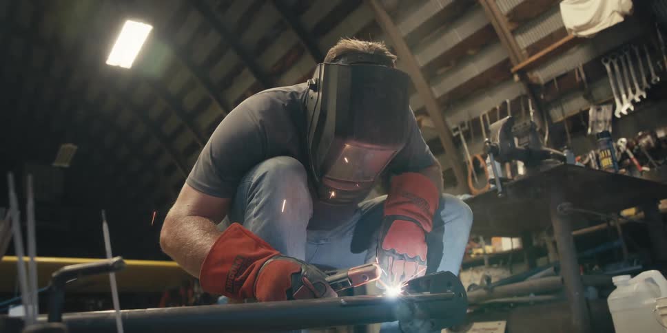 A person in protective gear is welding metal pieces together with bright sparks flying