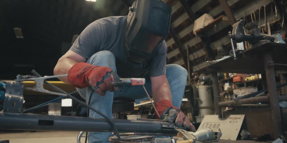 Crouched man with protective helmet welding a metal