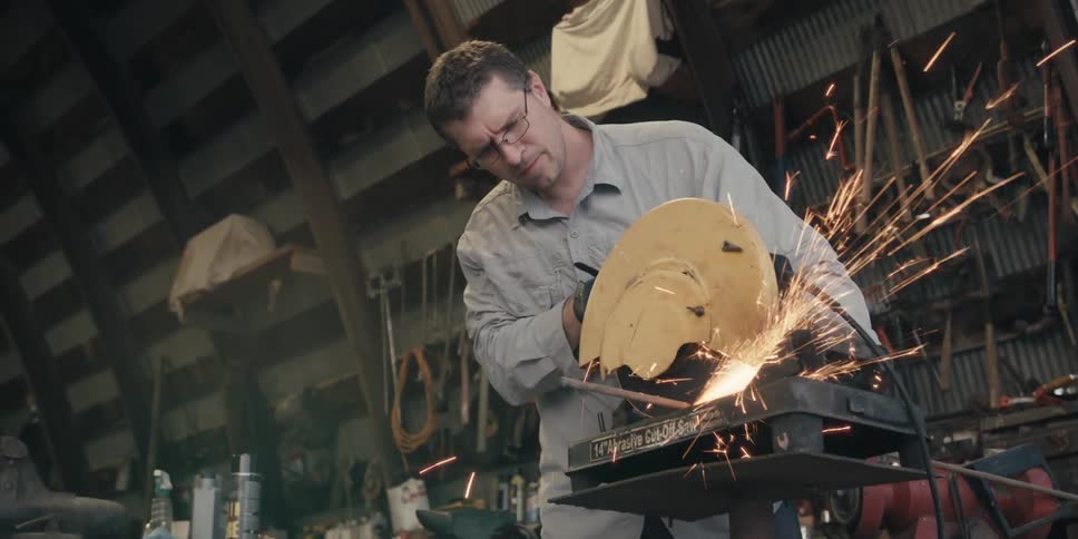 A man is using a circular saw to cut a metal rod
