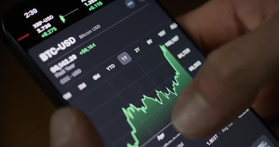 A persons finger moving the screen of a cell phone that has investment graphs and several texts