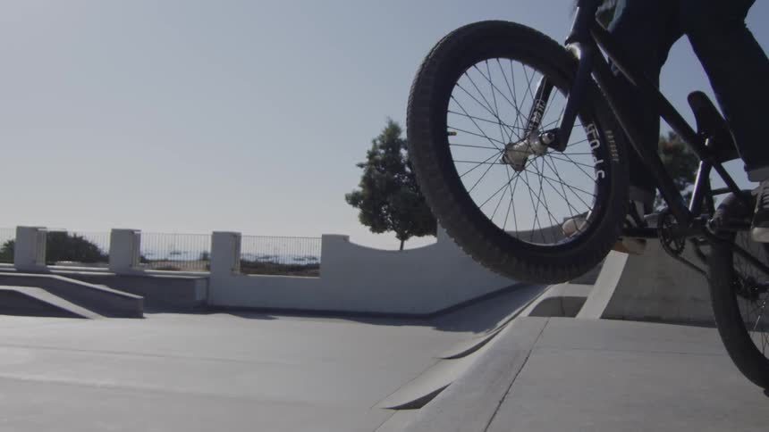 A man does a bike trick on a cement ramp