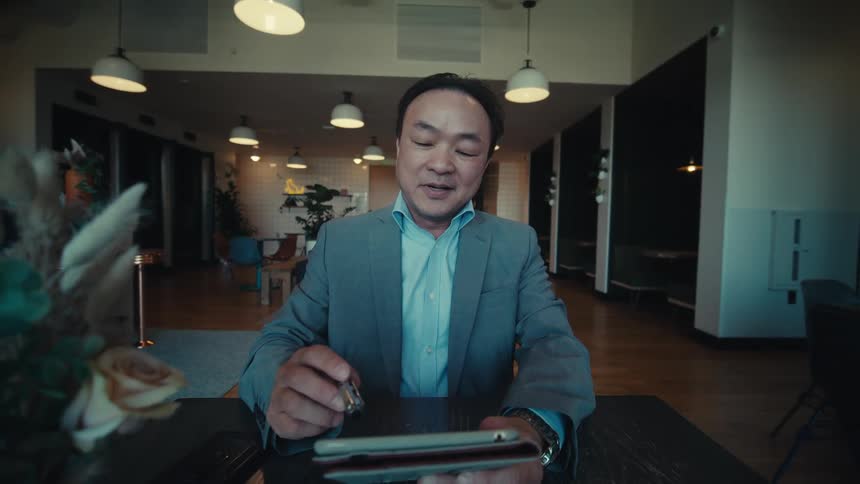 A man smiles as he taps his tablet with a sylus