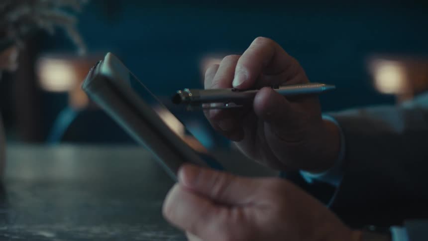Pair of hands with a pen interacting with a tablet