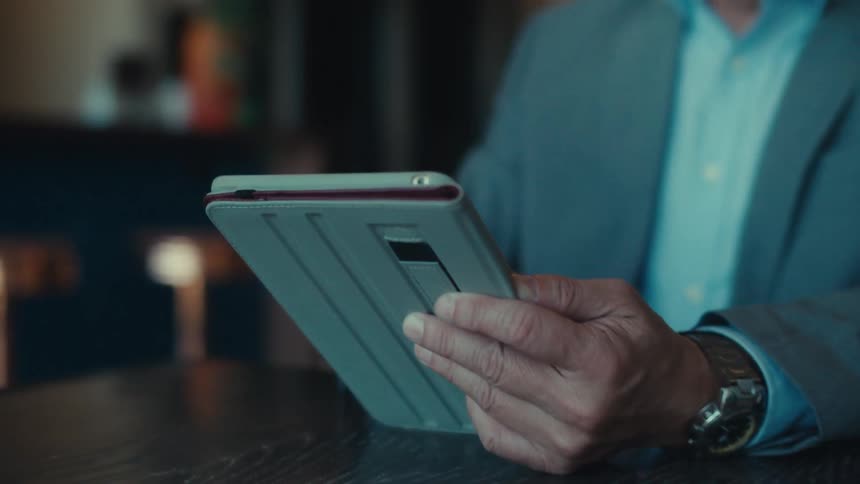 A person in a suit is sitting at a table in a modern stylish caf with a tablet