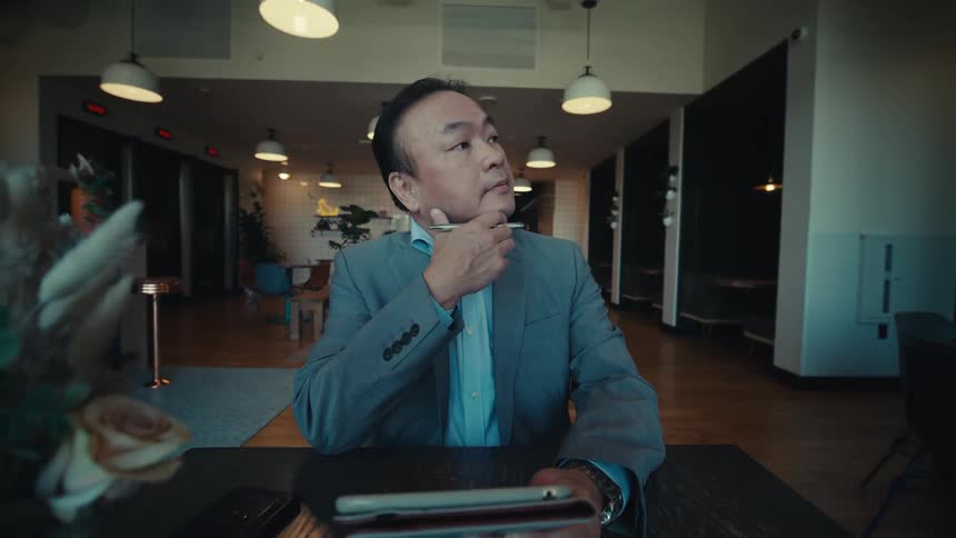 A person in a suit is sitting at a table in a modern stylish caf with a tablet