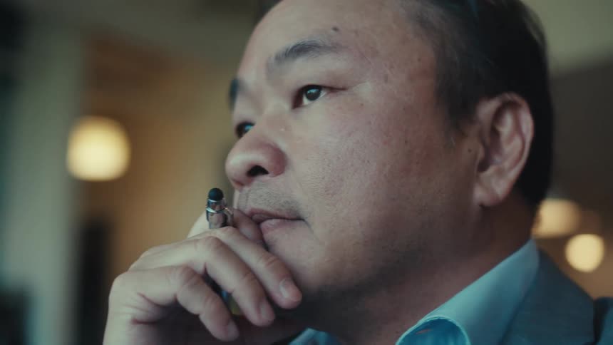 A person in a blue suit is deep in thought while working on a tablet
