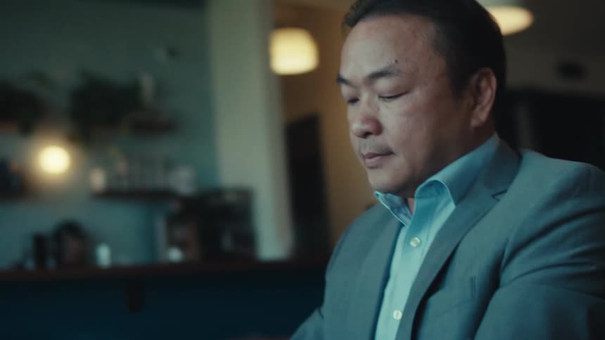 A person in a suit is sitting at a table in a modern stylish caf with a tablet