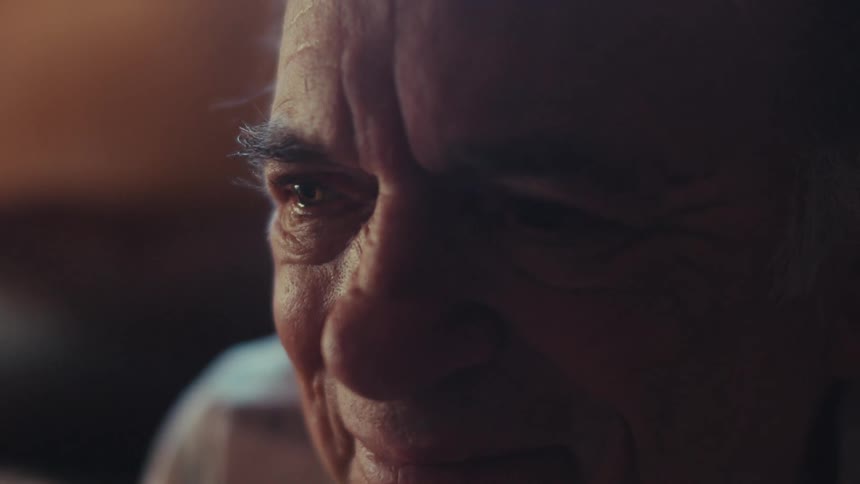 Closeup of an elderly man smiling with teary eyes reminiscing fond memories