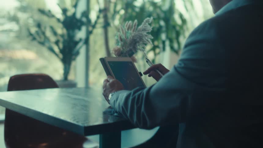 Businessman in a suit sits at a desk in the office using a tablet