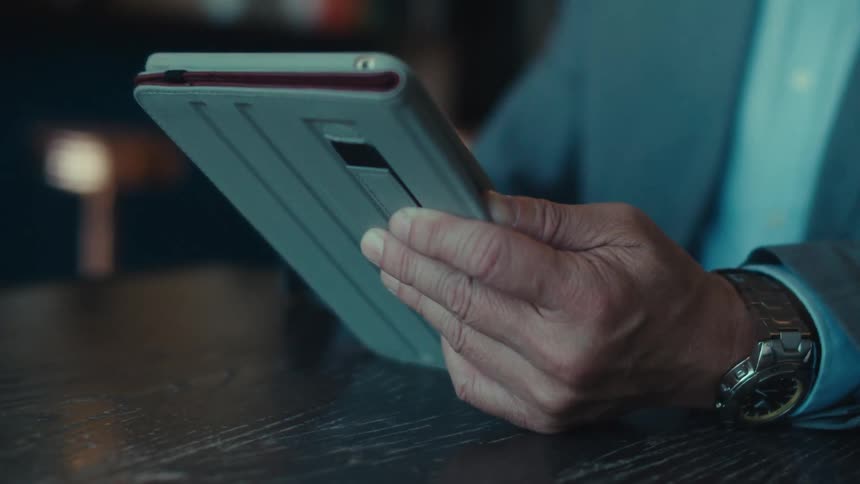 A person in a suit is sitting at a table in a modern stylish caf with a tablet