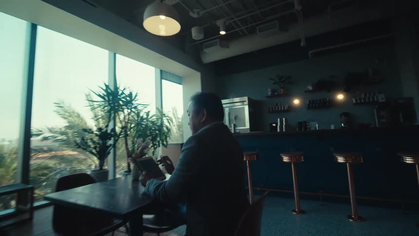 Man in a suit sitting at a table in a kitchen area in an office