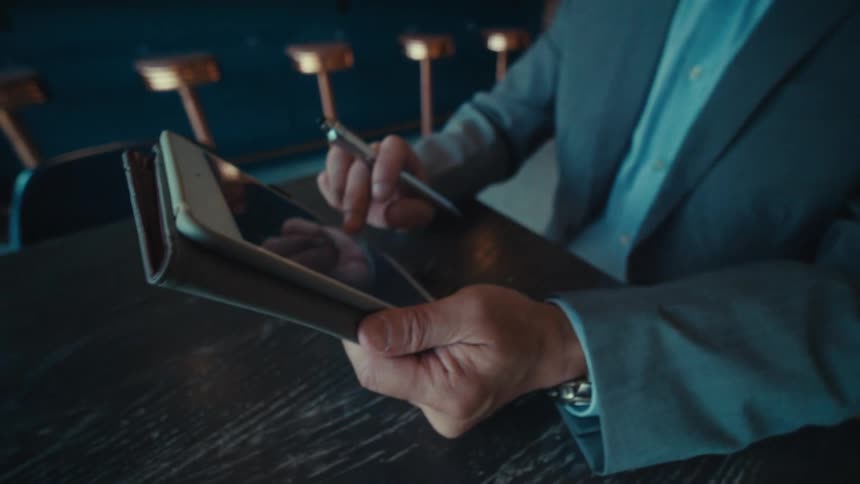 A man smiles as he uses his tablet
