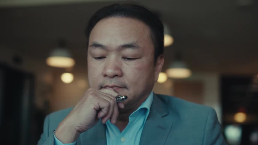A person in a blue suit is resting their chin on their hand working on a tablet