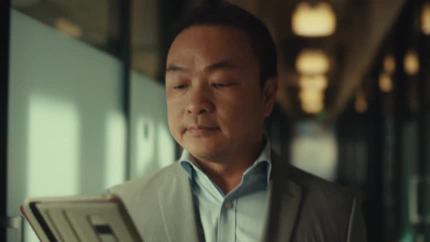 Office worker walks through a hallway in an office building while reading a tablet