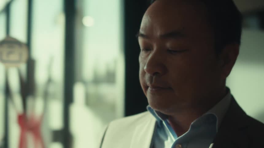 A person in a suit is walking down a modern office hallway while looking at a tablet