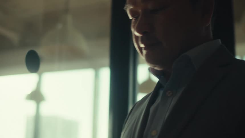 A man looks at his tablet as he walks through a room