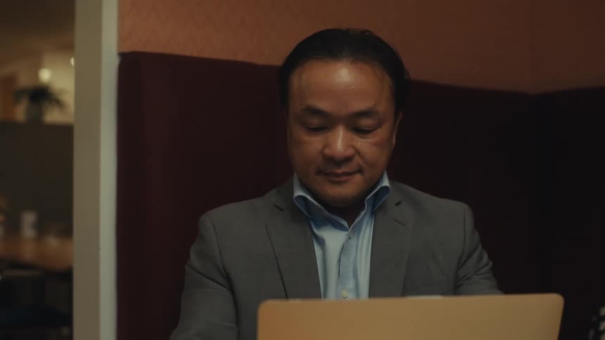 A man sits down and opens his laptop