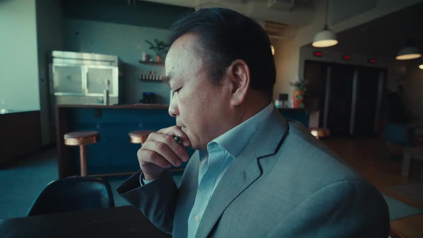A person in a suit is sitting at a table in a modern stylish cafe with a tablet