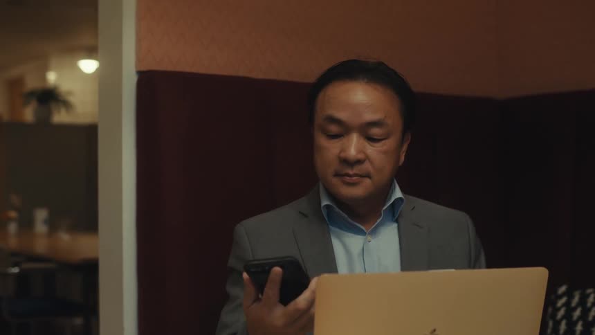 Timelapse of a person sitting down to work in a room with a laptop and a smartphone
