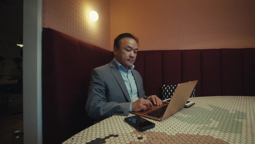 A person in a suit is sitting at a table in a modern stylish caf with a laptop