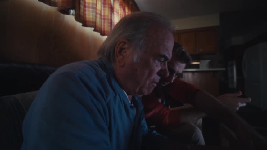A man helps an older man with his cellphone