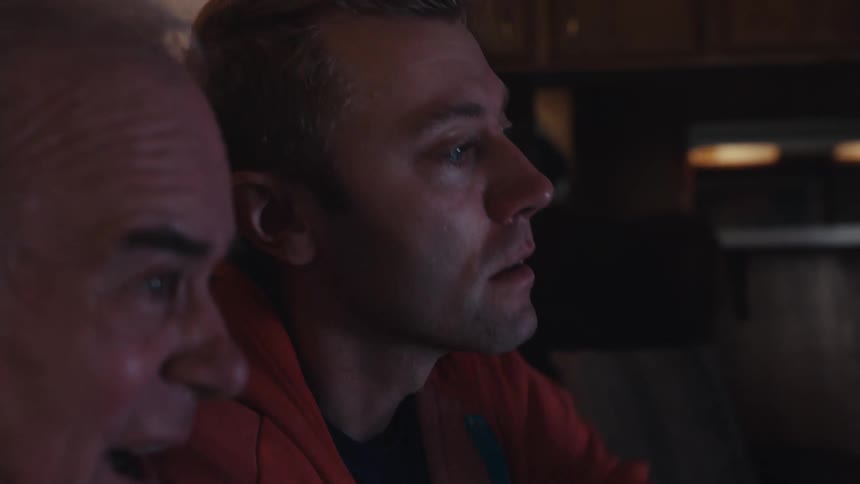 Two men are sitting on the sofa and talking while looking intently ahead