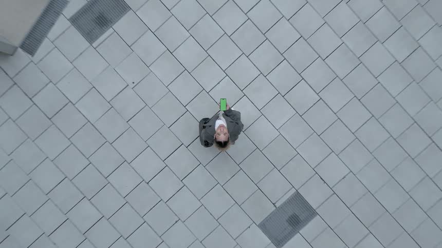 A woman using a cell phone with a green screen seen from above