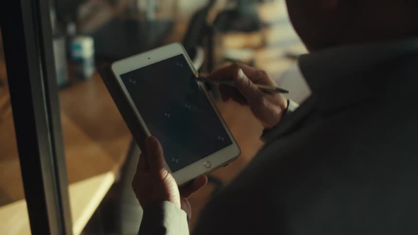 A man is using a stylus on his tablet