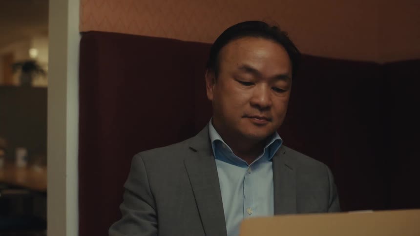 A man is talking on his cell phone in front of his laptop