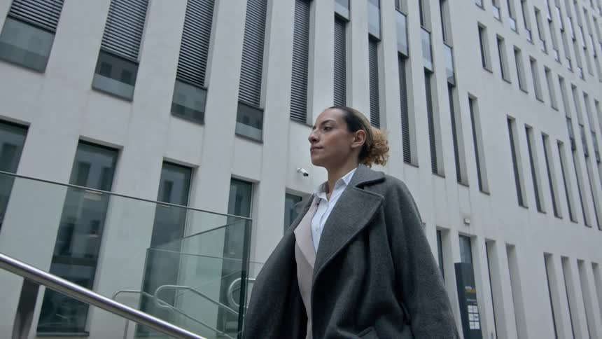 Businessperson walks past an office building during the day