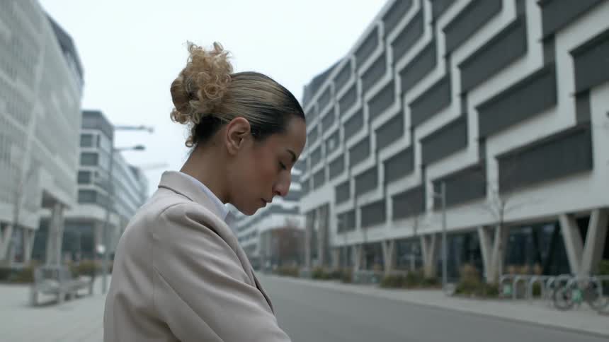 A woman takes a phone out of her bag in front of the building