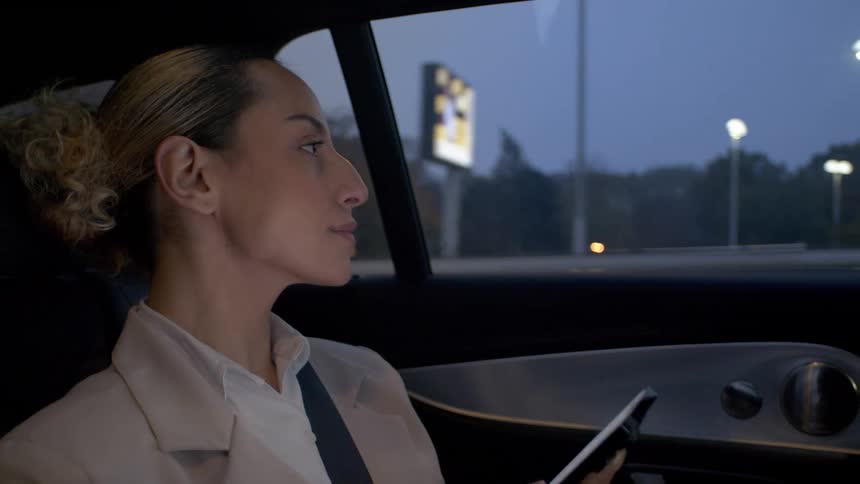 A woman is holding her phone as she rides in a car